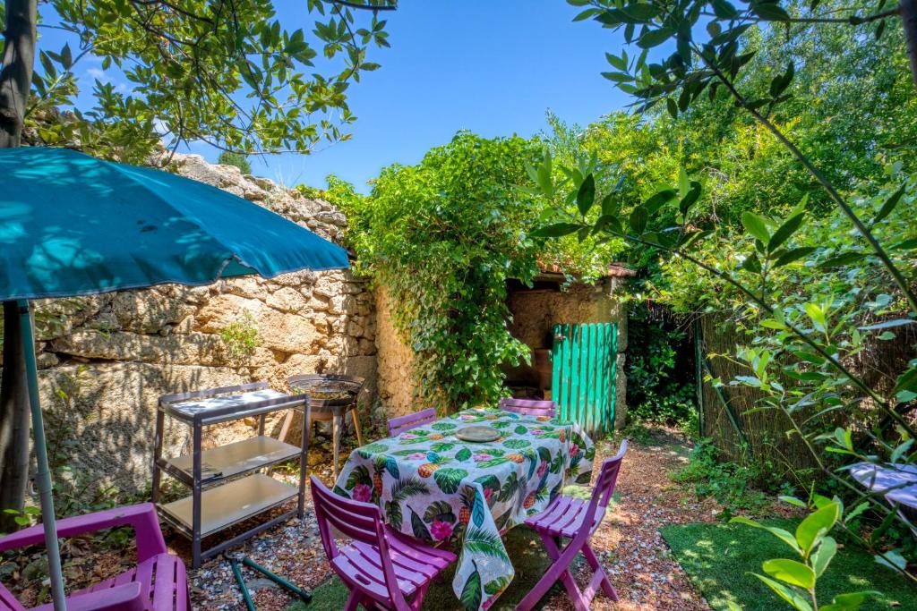 un giardino con tavolo, sedie e ombrellone di Gîte Gaia a Poussan