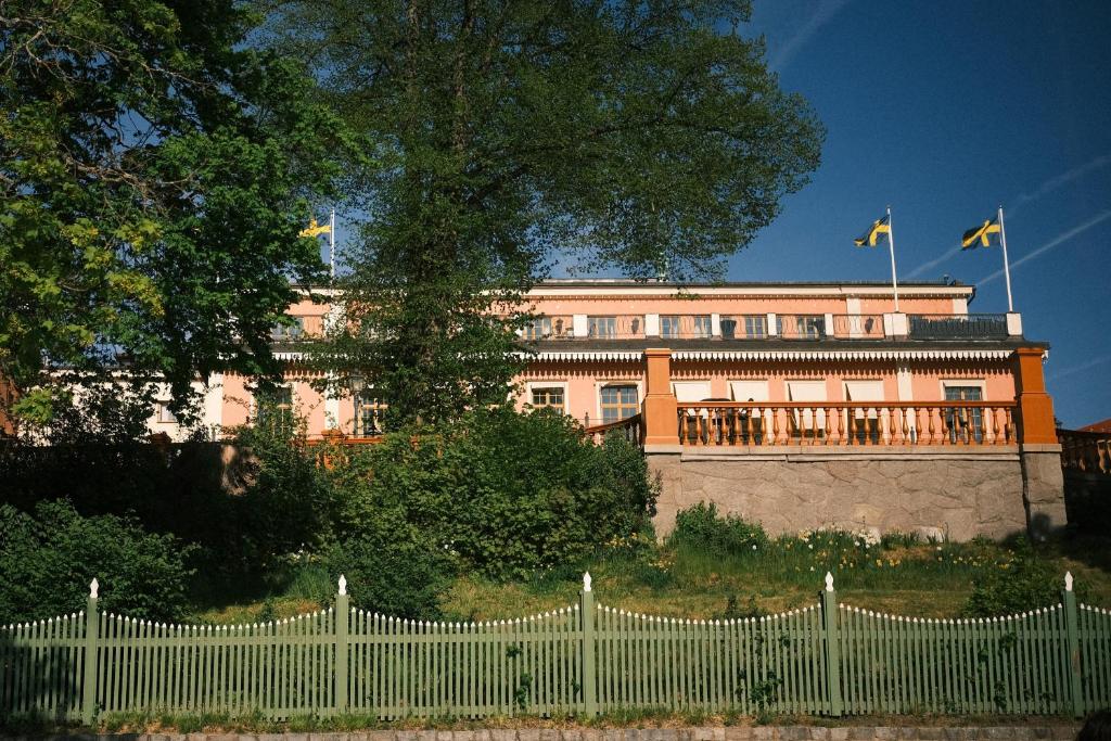 uma cerca branca em frente a um edifício com bandeiras em Hotel Hasselbacken em Estocolmo