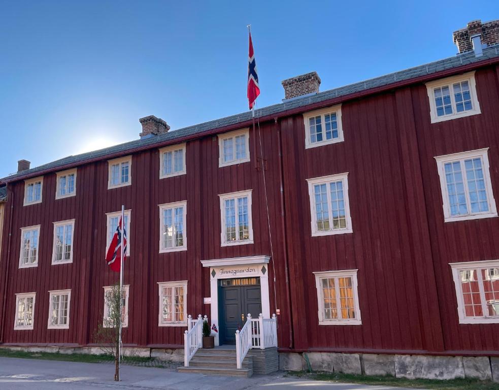 un edificio rojo con dos banderas delante en Finnegården Røros, en Røros