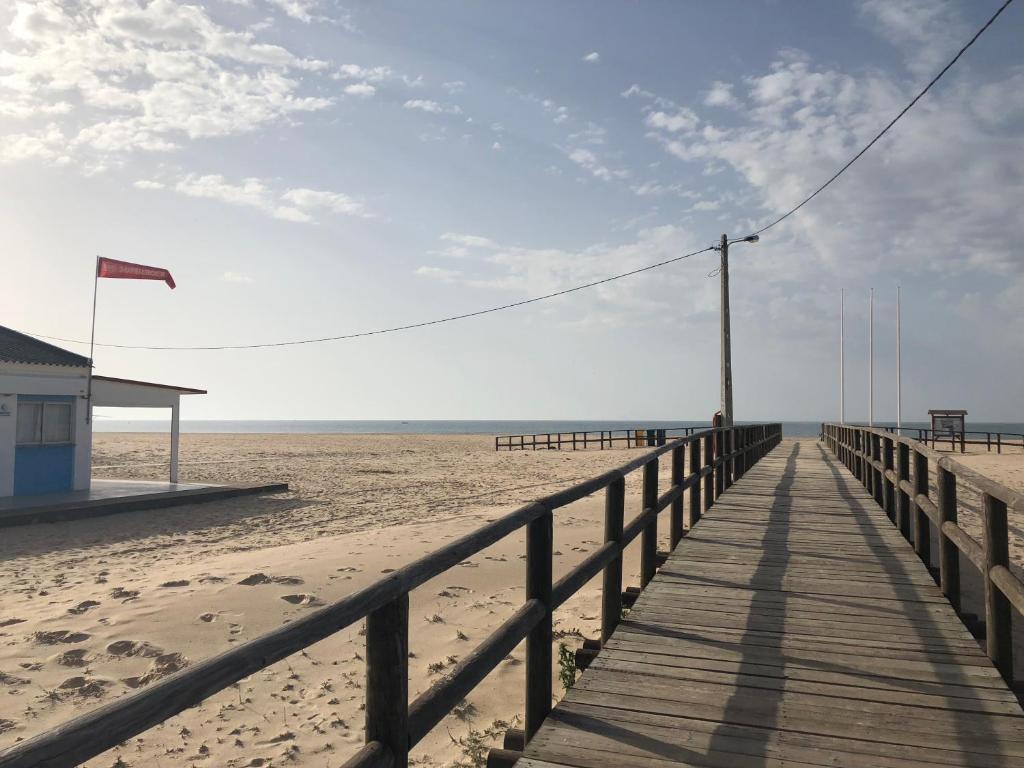 un paseo marítimo de madera que conduce a una playa con un edificio en Idéal villa, en Vila Nova de Cacela