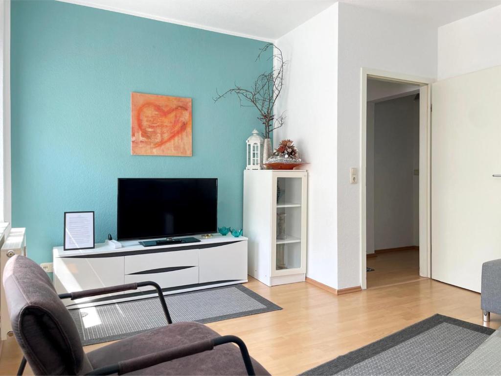 uma sala de estar com uma televisão de ecrã plano numa parede azul em Gemütliches Apartment, Seenähe, WM, WLAN, Balkon em Markkleeberg