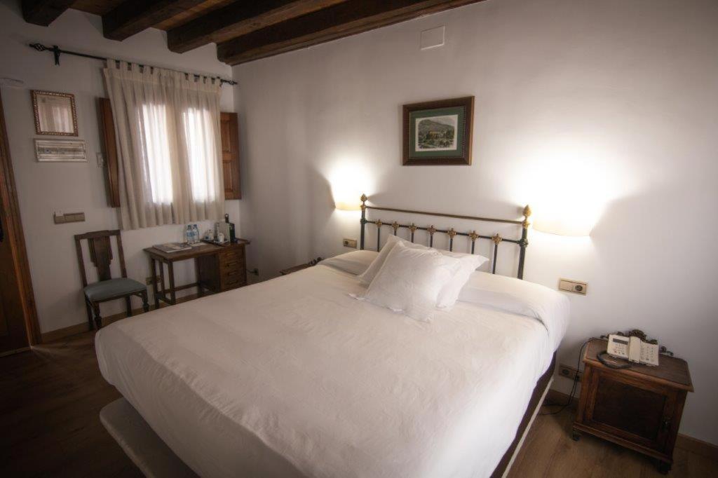 een slaapkamer met een groot wit bed en een tafel bij Hotel Rural Abadía de Yuste in Cuacos de Yuste