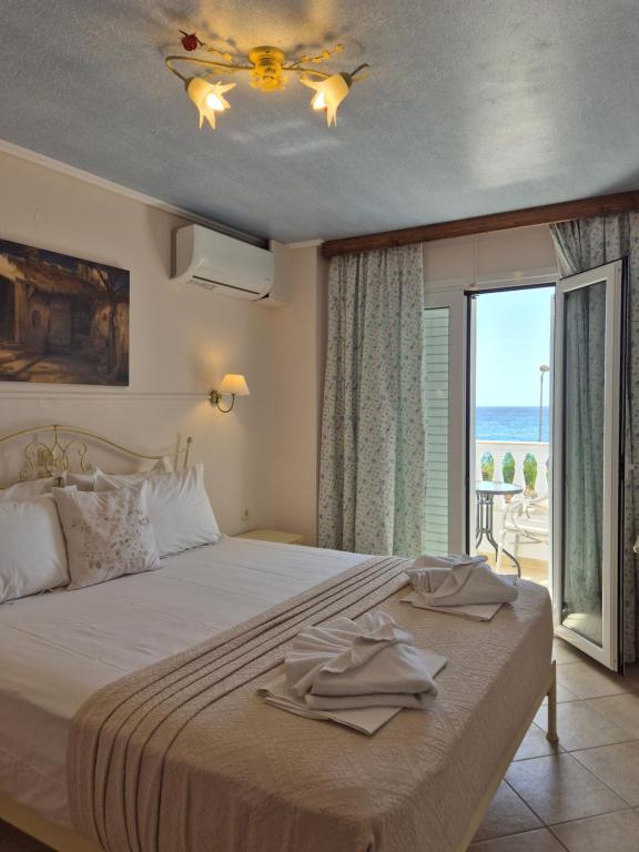 1 dormitorio con 1 cama, ventilador de techo y ventana en Vrachos Beach Hotel, en Vrachos