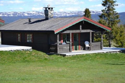 una piccola casa su una collina con montagne sullo sfondo di Lifjellhytte 10 by Norgesbooking - cabin at Golsfjellet a Gol