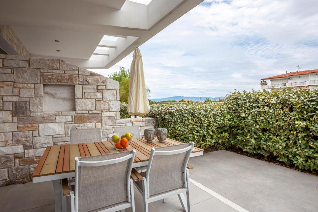 a patio with a wooden table and chairs and a stone wall at Villa Selena seafront in Hanioti