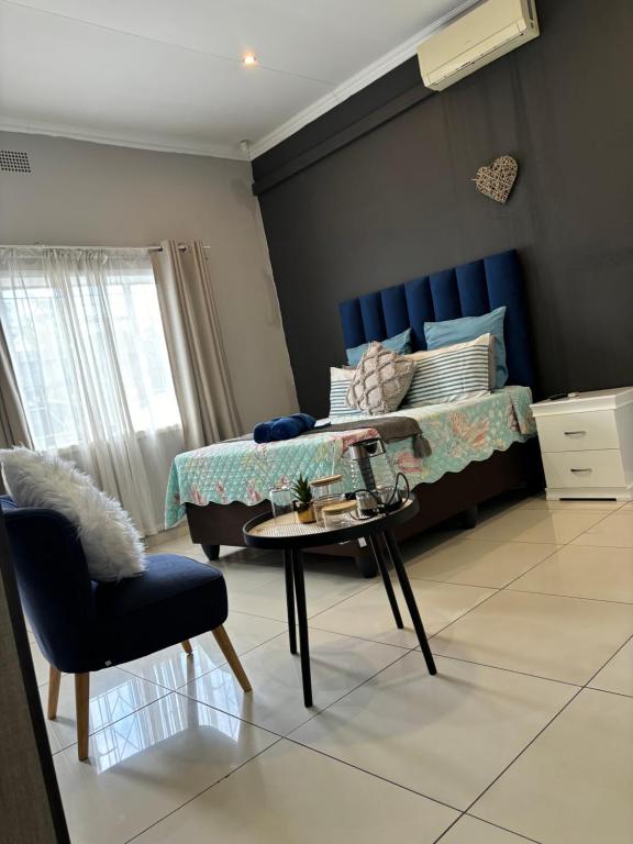 a bedroom with a bed and a table and a chair at Sleepover @194 in Rustenburg