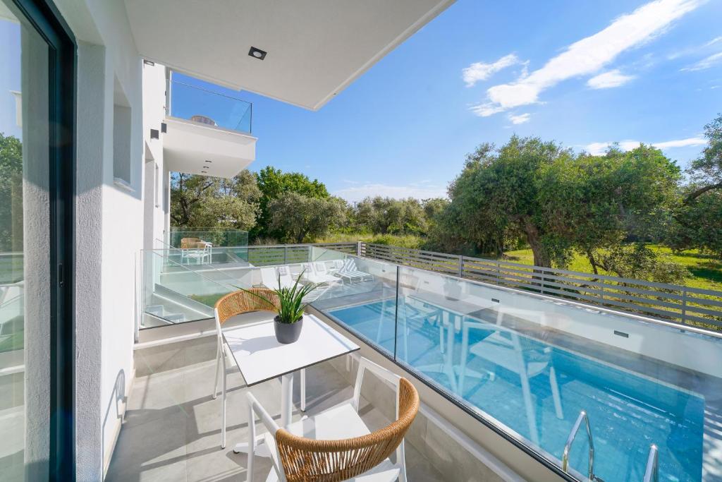 balcón con mesa y sillas y piscina en Nuevo Suites en Limenas