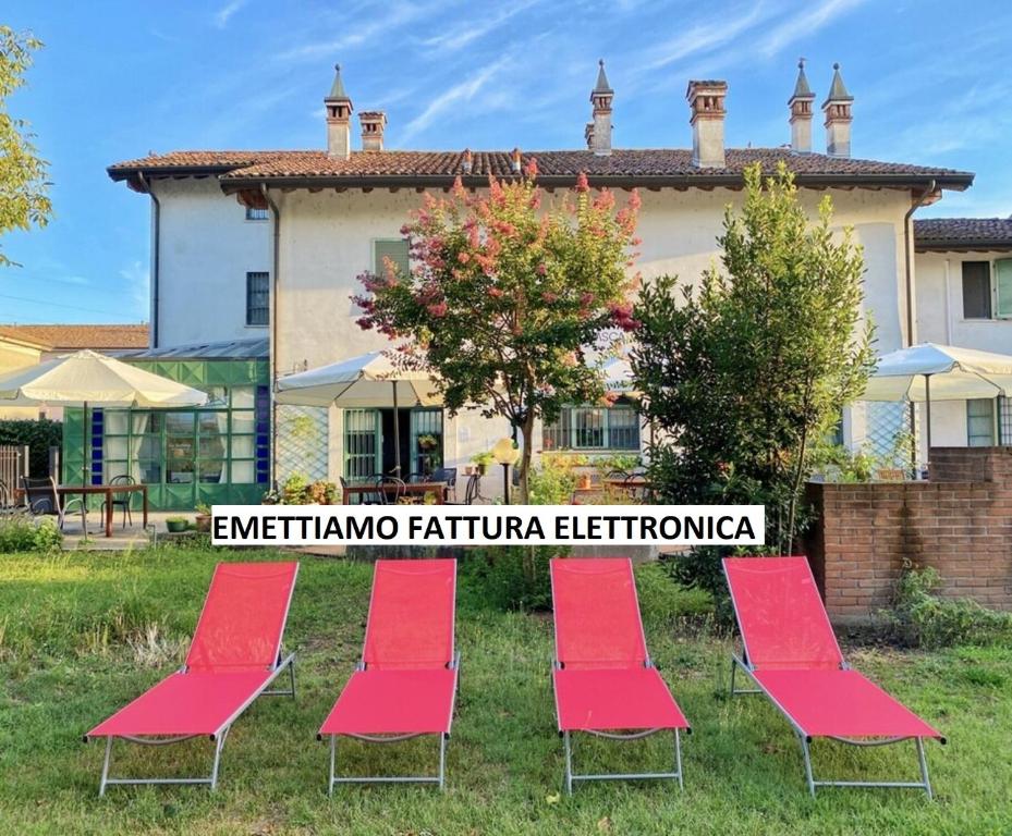 a group of red chairs in front of a building at La Borasca - B&B in Casalpusterlengo