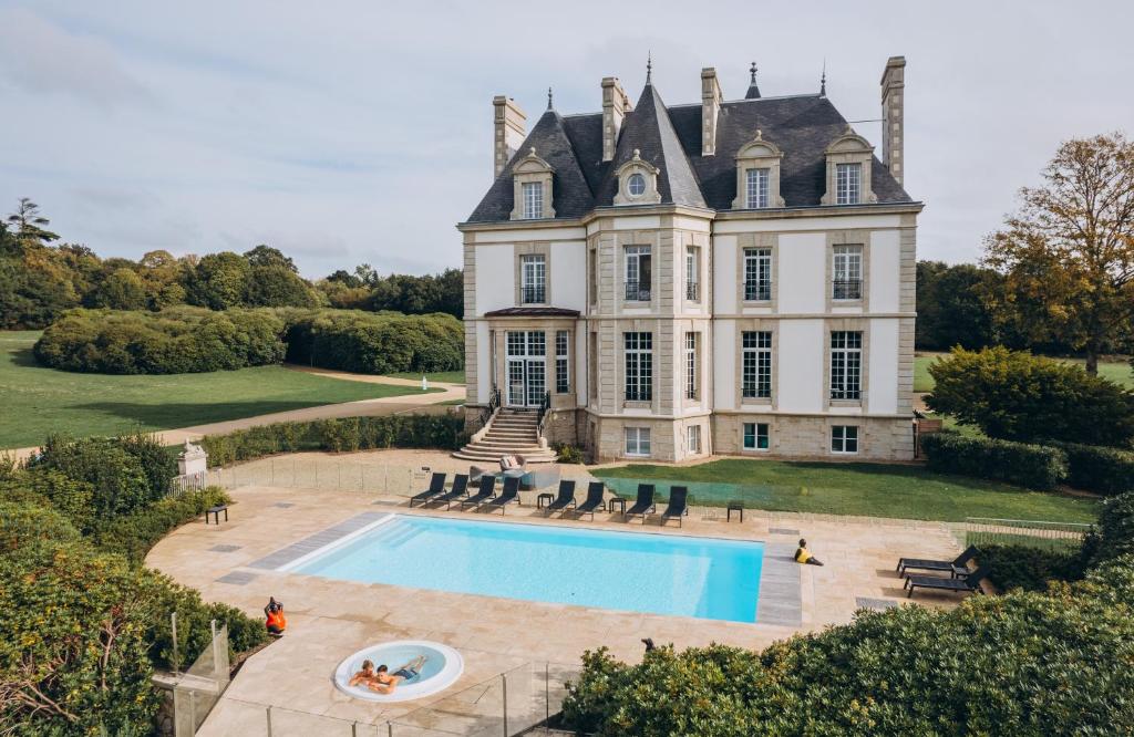 un domaine avec une piscine en face d'une maison dans l'établissement Les Garennes - Hôtel Spa Bénodet, à Bénodet