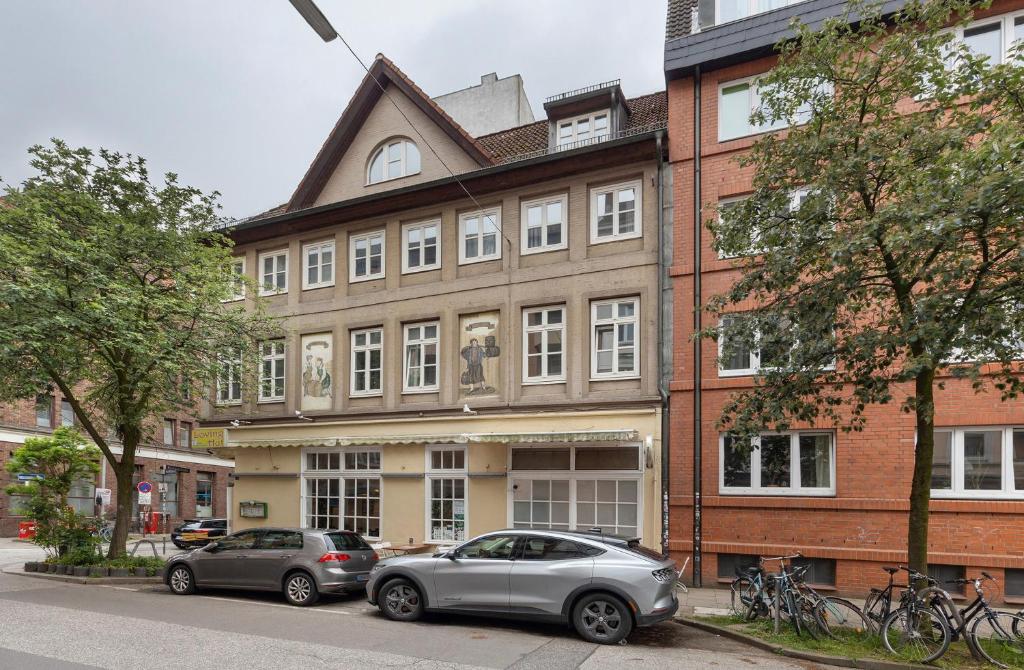 漢堡的住宿－Wunderschöne 3 Zimmer Wohnung，两辆汽车停在大楼前
