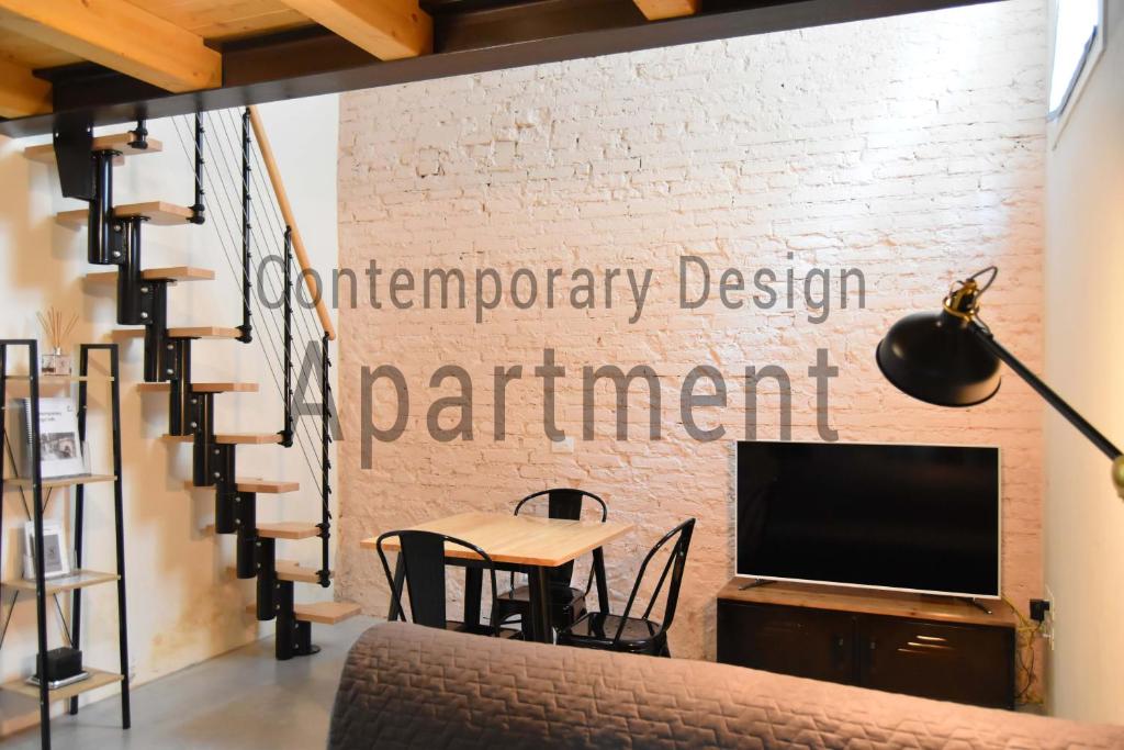 Contemporary Design Loft & Apartment Padova في بادوفا: غرفة معيشة مع طاولة وتلفزيون وجدار من الطوب