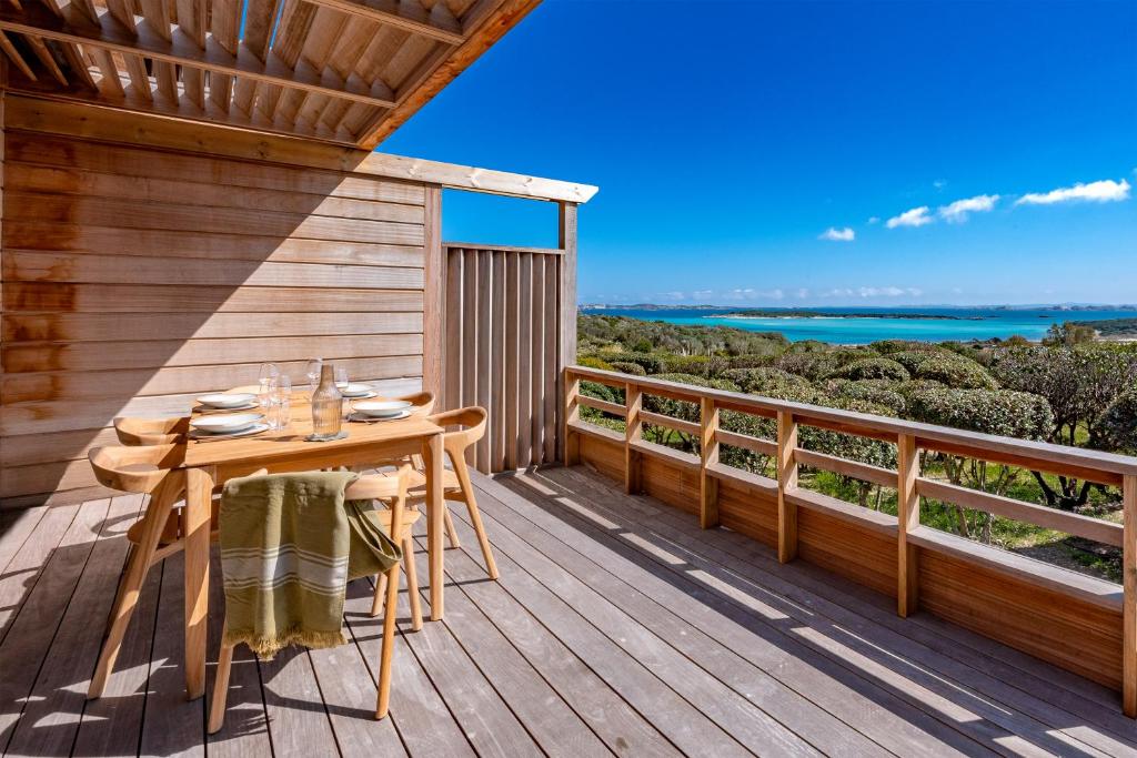 une terrasse en bois avec une table et des chaises dessus dans l'établissement Hameau de Piantarella, à Bonifacio