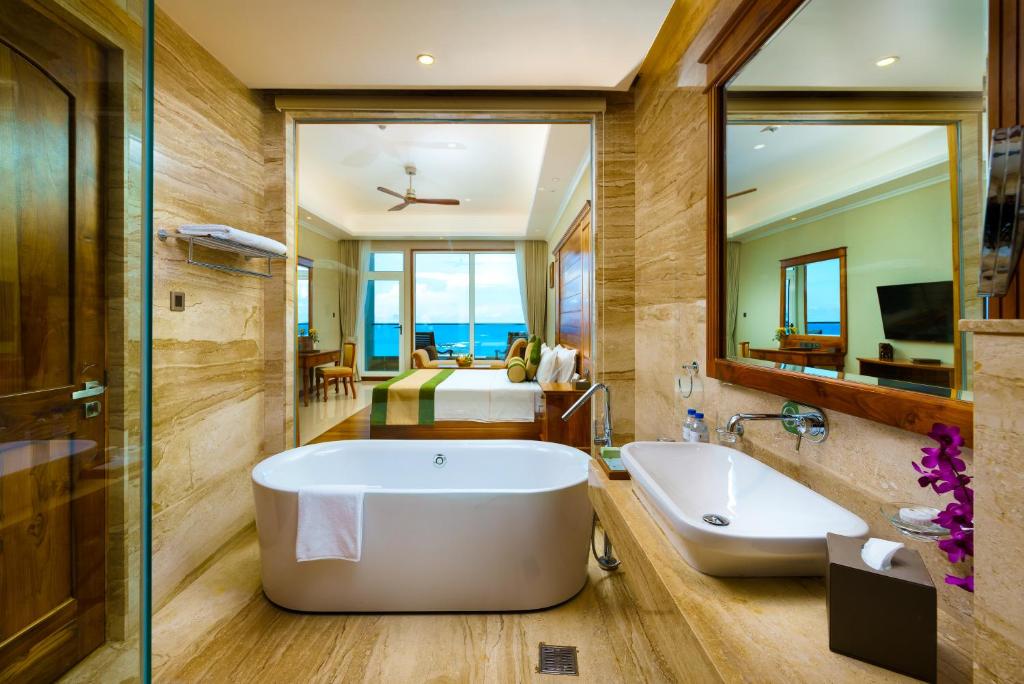 a bathroom with a tub and a bedroom at Araliya Beach Resort & Spa Unawatuna- Where you meet the sea all year in Unawatuna