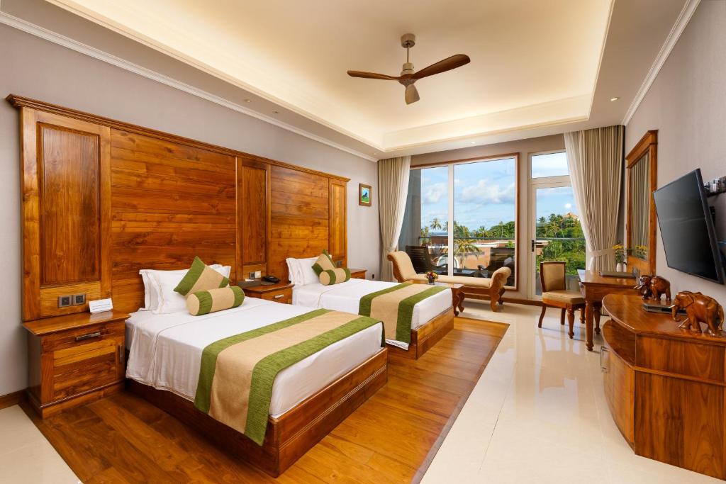 a hotel room with two beds and a flat screen tv at Araliya Beach Resort & Spa Unawatuna- Where you meet the sea all year in Unawatuna