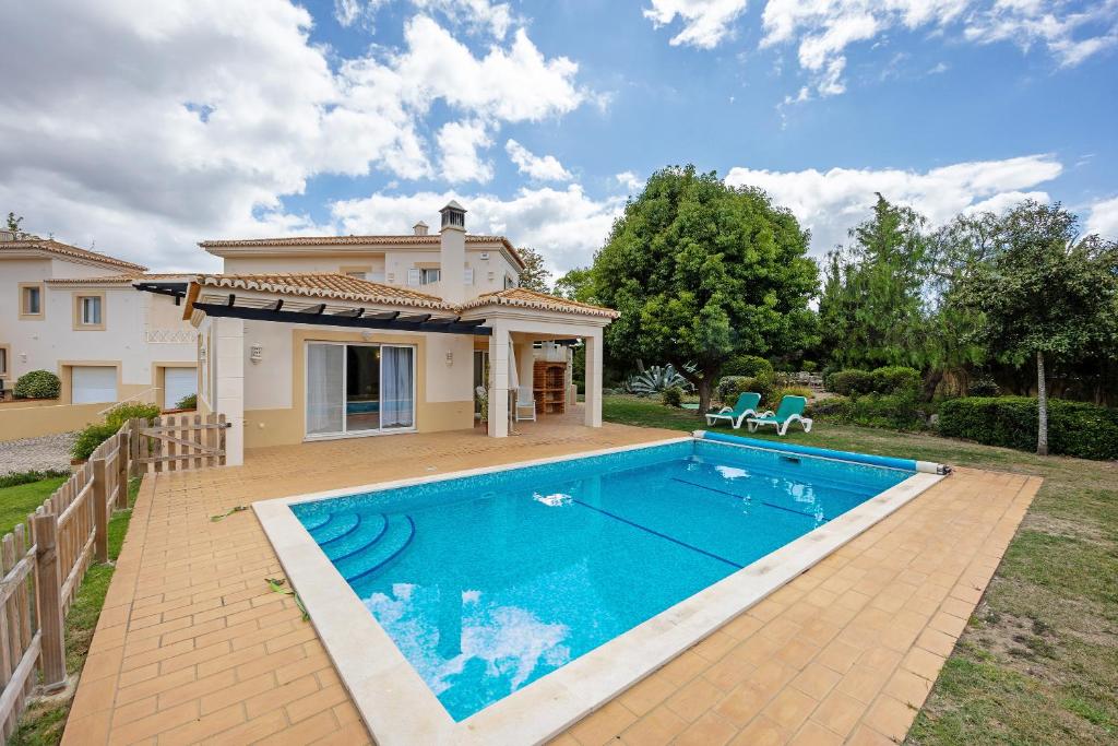 uma villa com piscina em frente a uma casa em Moradia 170 em Lagoa