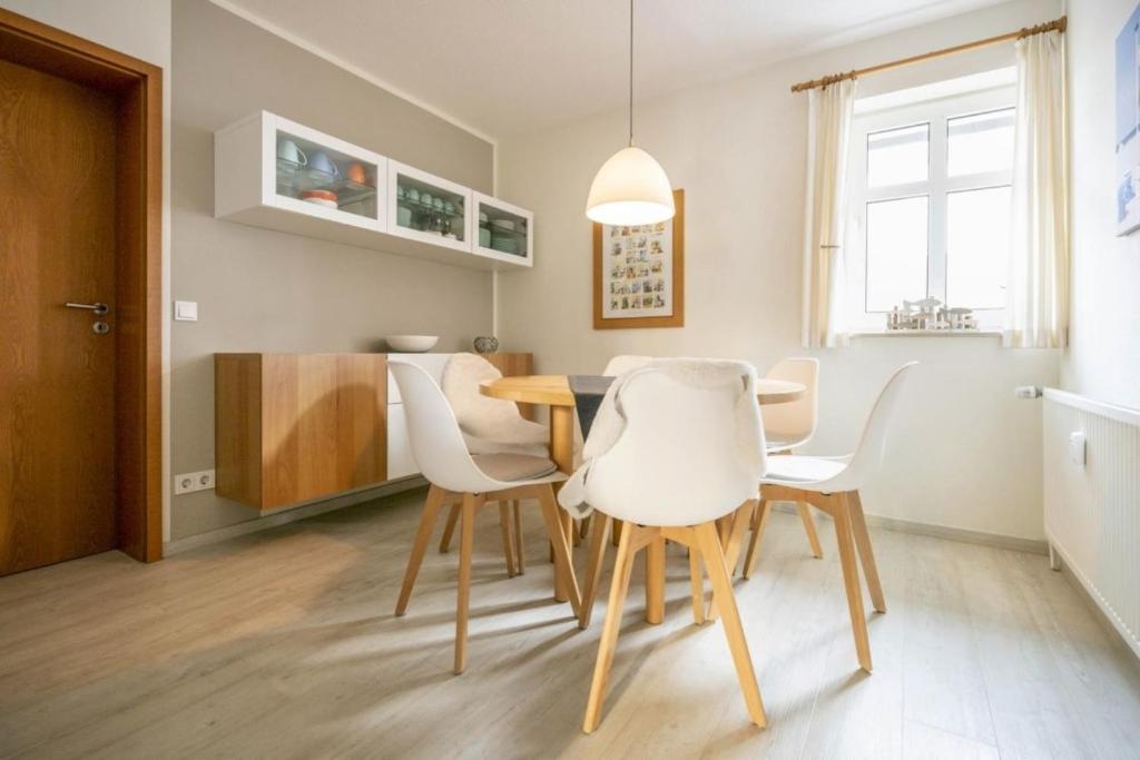 a dining room with a table and white chairs at Strandburg 207 in Juist