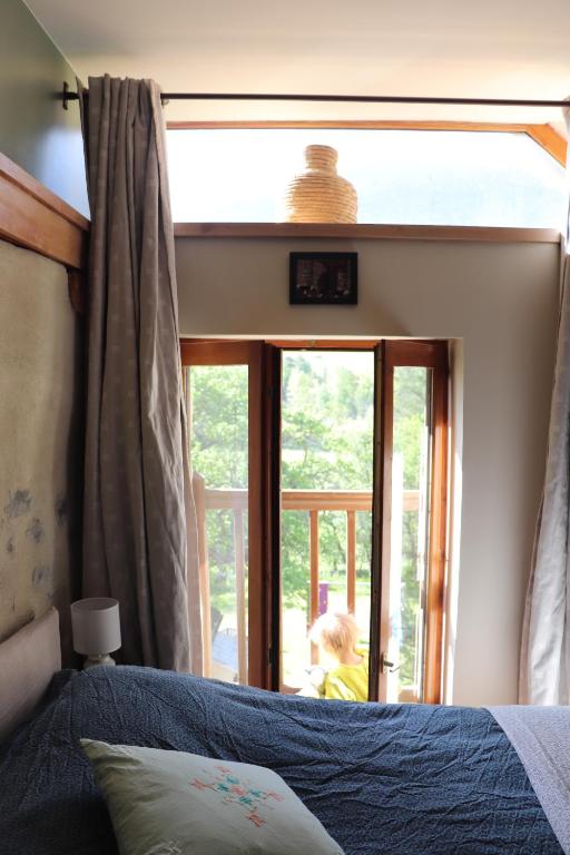 - une chambre avec un lit et une grande fenêtre dans l&#39;établissement Appartement dans une maison de pays, à Briançon