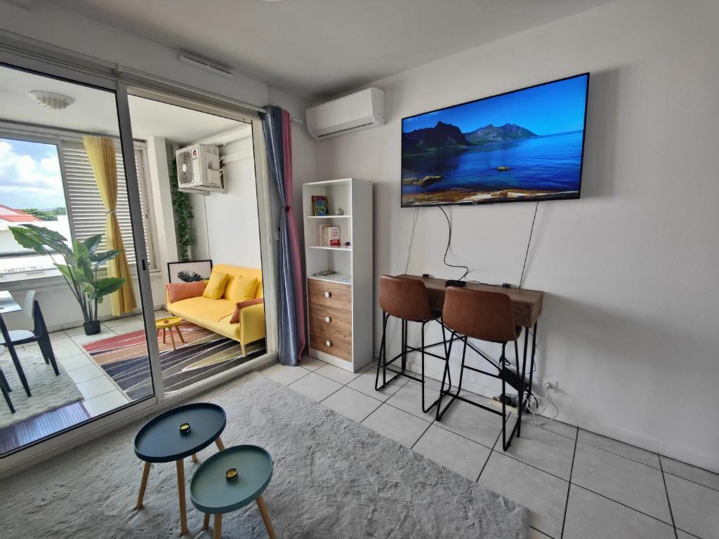 a living room with a flat screen tv on the wall at Studio Vanille - Vue Mer in Saint-Denis
