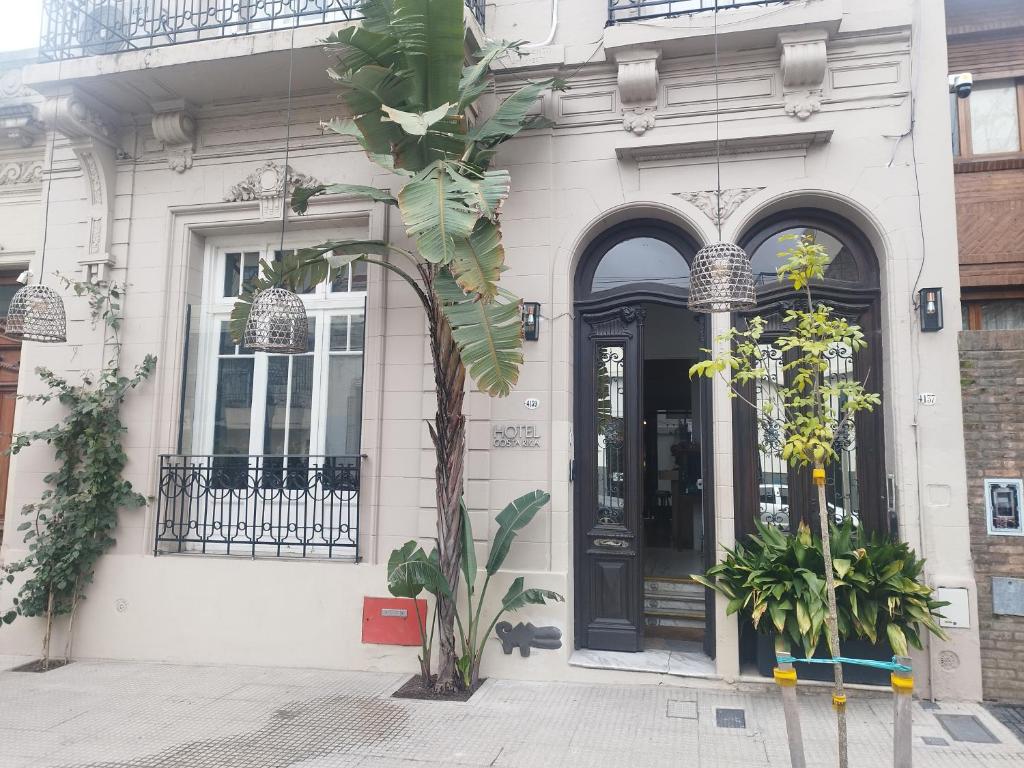 a white building with a black door and a tree at Hotel Costa Rica in Buenos Aires