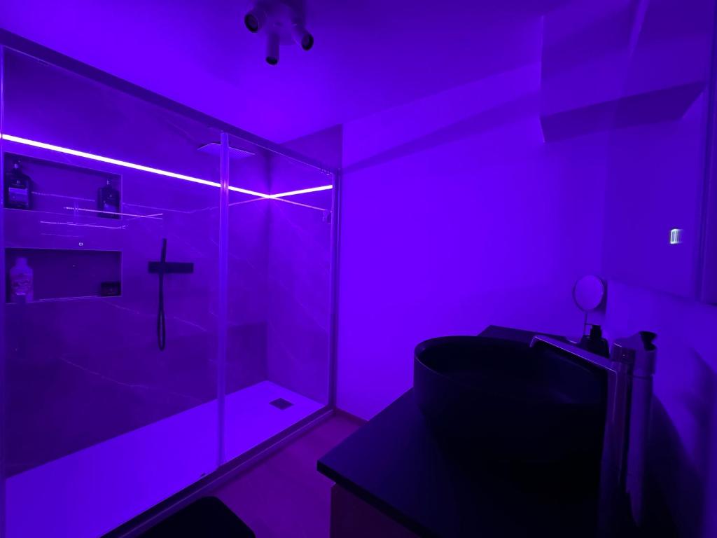 La salle de bains est pourvue d'une douche avec une lumière violette. dans l'établissement Duplex 100m2 style contemporain, à Seraing