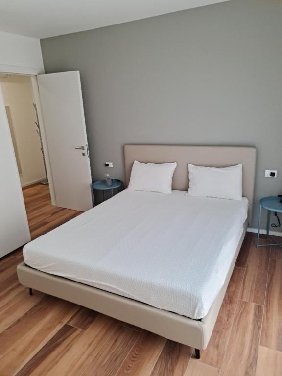 un grande letto bianco in una camera con pavimenti in legno di Casa Baso - Agenzia Caorle a Caorle