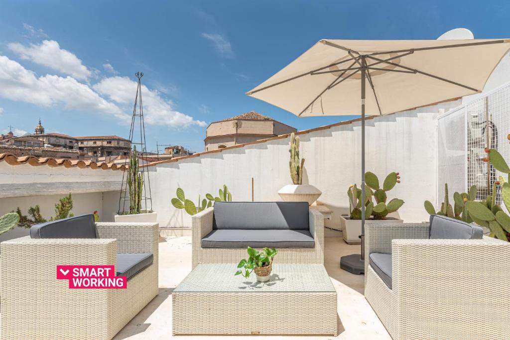 un patio con sillas, una mesa y una sombrilla en Cala Loft by Wonderful Italy, en Palermo