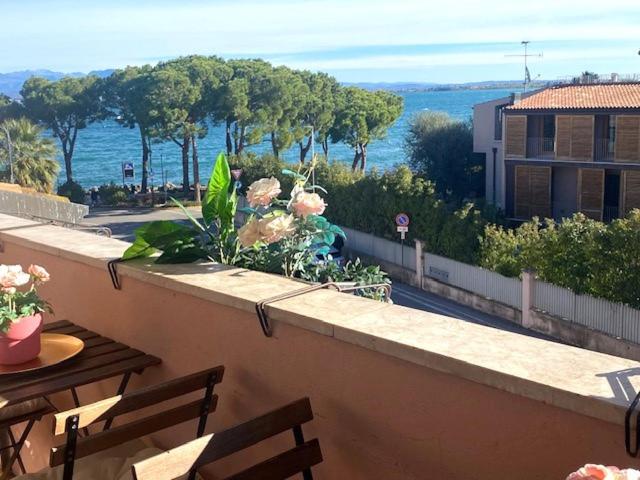 balcone con tavoli, sedie e vista sull'oceano di Blue Lake Home Luxury Appartment a Desenzano del Garda