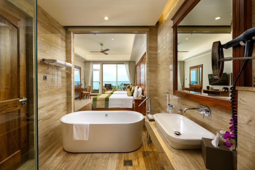 a bathroom with a tub and a large mirror at Araliya Beach Resort & Spa Unawatuna- Where you meet the sea all year in Unawatuna