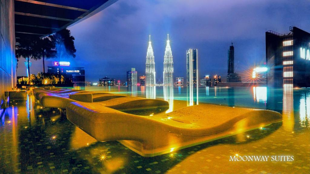 une rangée de bancs dans une ville la nuit dans l'établissement MOONWAY SUITES At EATON KLCC, à Kuala Lumpur