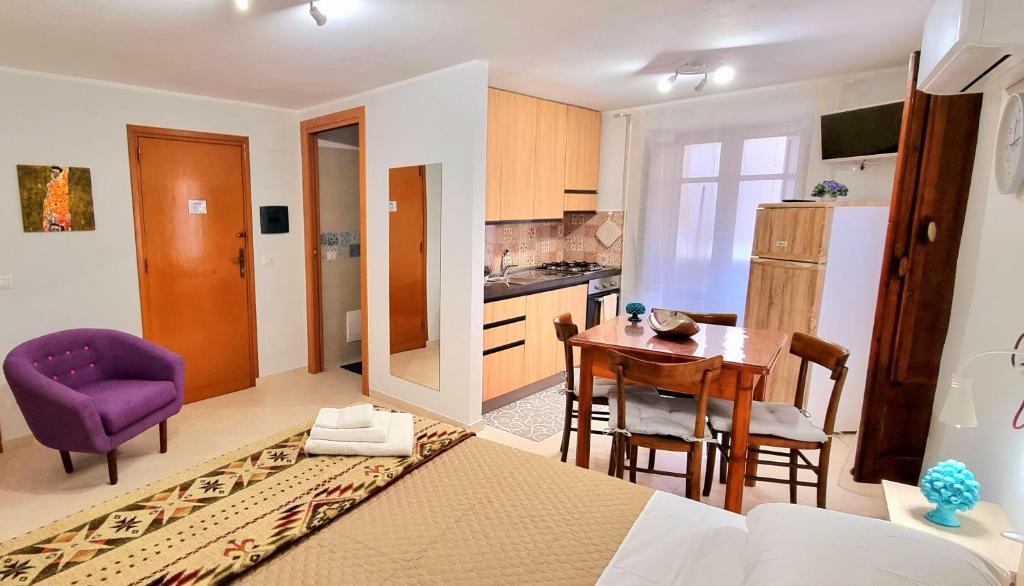 una cucina e una sala da pranzo con tavolo e sedia viola di Porta Terra Apartment a Cefalù
