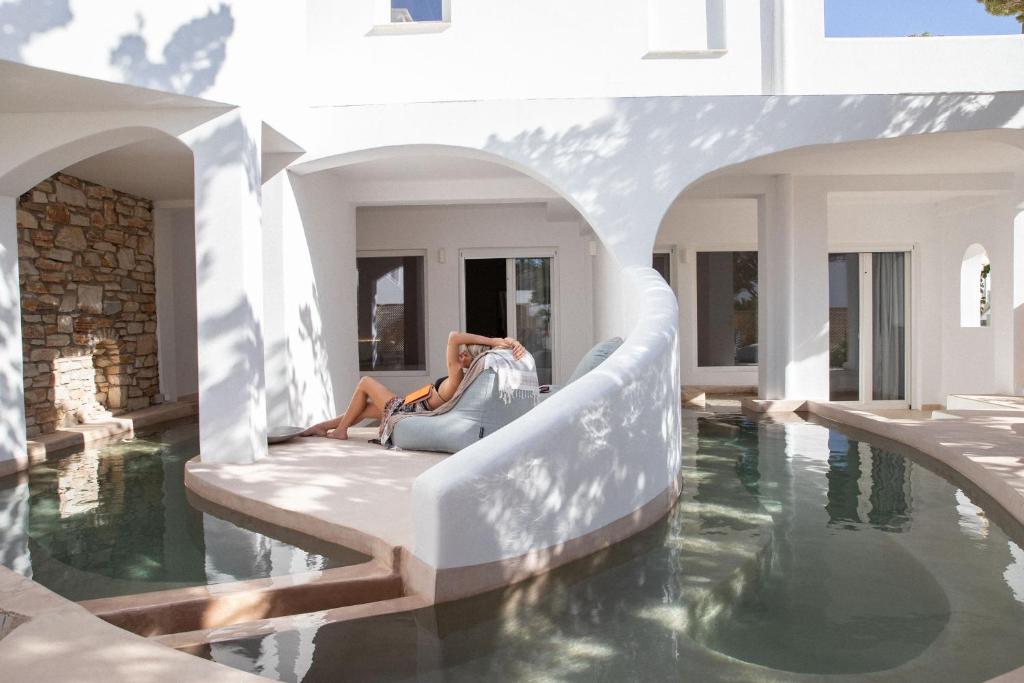 Aloni Hotel & Suites في بوسي لفاذي: امرأة جالسة على أريكة بجوار حمام سباحة
