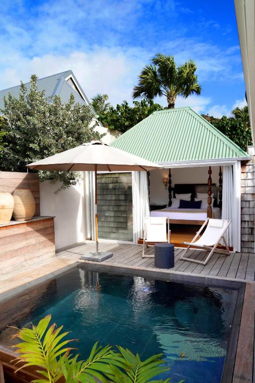 a swimming pool with an umbrella next to a house at Exceptional villa with pool and spa, Saint-Barthélemy. in Saint Barthelemy