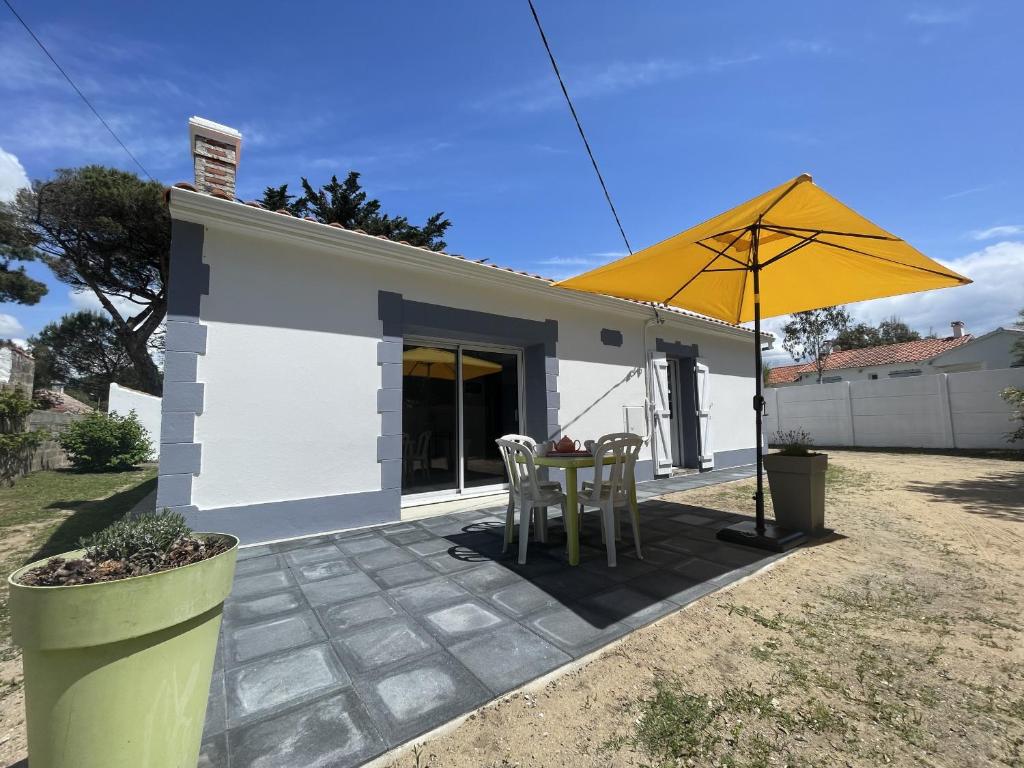 d'une terrasse avec une table et un parasol jaune. dans l'établissement La Sionnaise, à Plage-des-Demoiselles