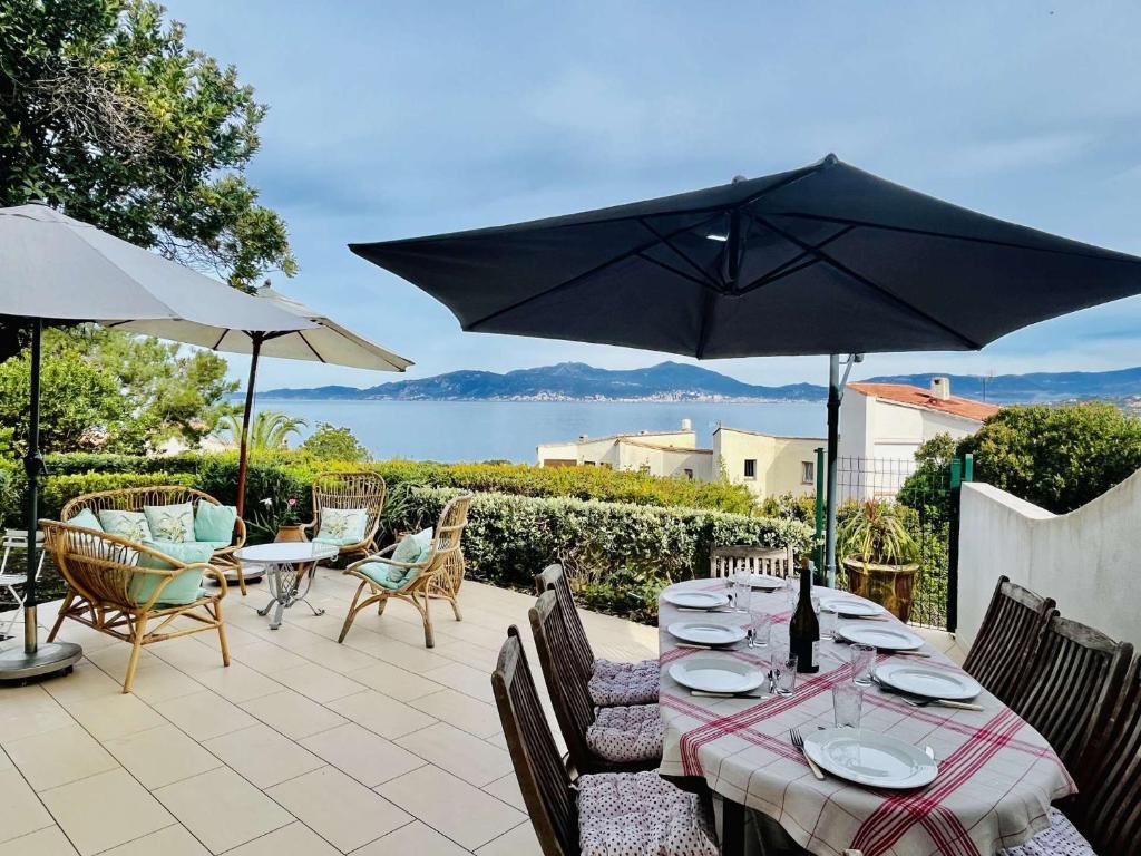 une table avec des chaises et un parasol sur une terrasse dans l'établissement Maison 4 pièces PIETROSELLA, à Pietrosella