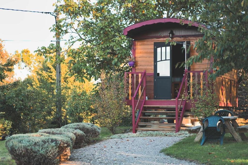 une petite cabine avec une porte rouge dans un jardin dans l'établissement Nid douillet en Ardèche, à Chomérac