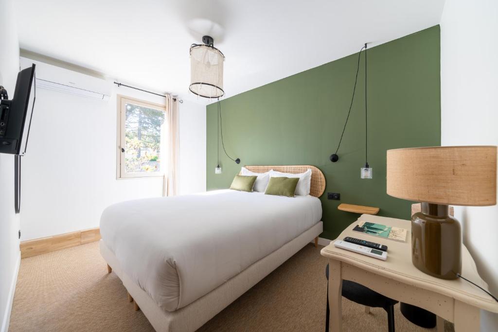 1 dormitorio con 1 cama y 1 mesa con lámpara en Hôtel La Garrigue & Bar Piscine, en Venasque