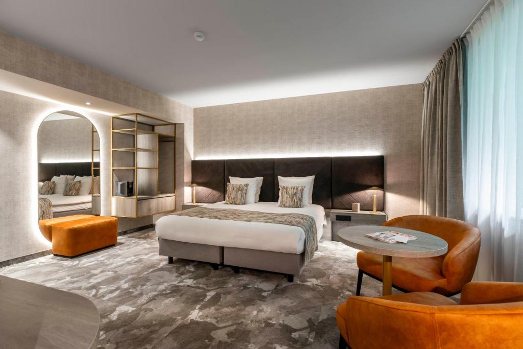 um quarto de hotel com uma cama, uma mesa e cadeiras em Van der Valk Waterloo em Waterloo