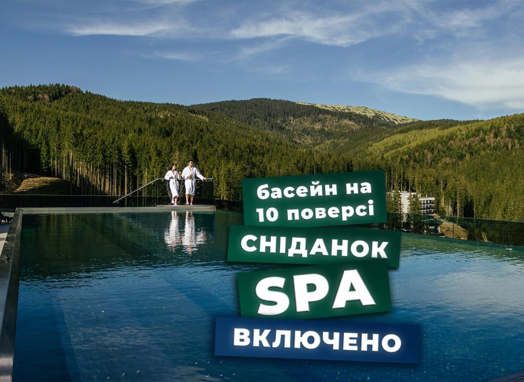 dos personas de pie en el borde de un charco de agua en Rest&Ski Spa Resort en Bukovel