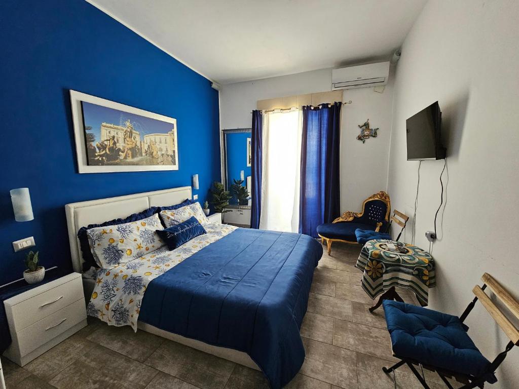 1 dormitorio azul con 1 cama y 1 silla en La Piccola Perla di Ortigia en Siracusa