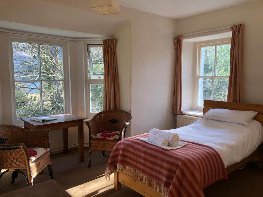 ein Schlafzimmer mit Bett, Schreibtisch und Fenstern in der Unterkunft Trigonos - Peaceful Lakeside B&B and Retreat in Eryri National Park in Caernarfon