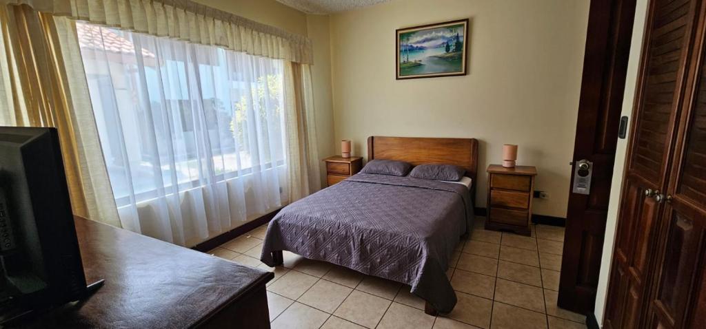 サンホセにあるApartotel Obelisco San José Aeropuertoのベッドルーム1室(ベッド1台、大きな窓付)