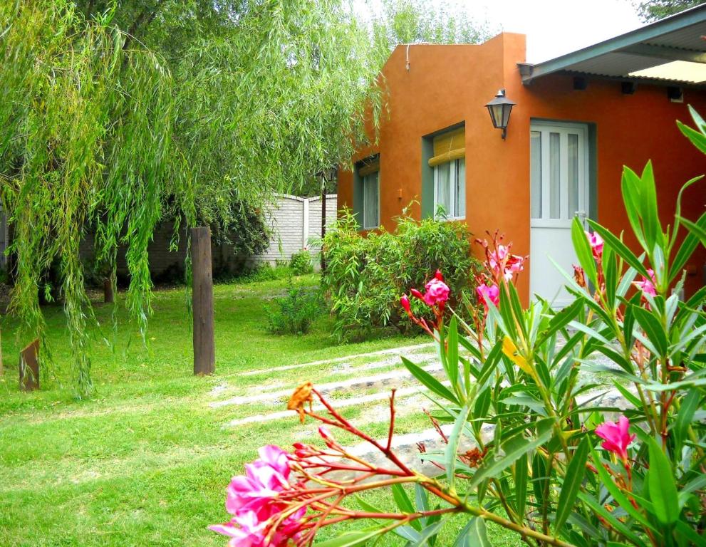 a garden with pink flowers in front of a house at Cabañas Ronca Hue in Tandil