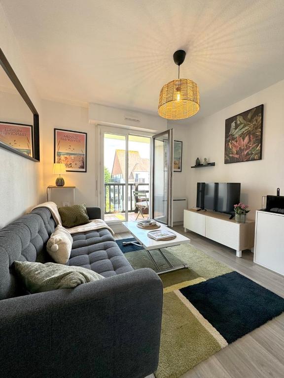 un salon avec un canapé et une télévision dans l'établissement Cabourg Plage 5, à Cabourg