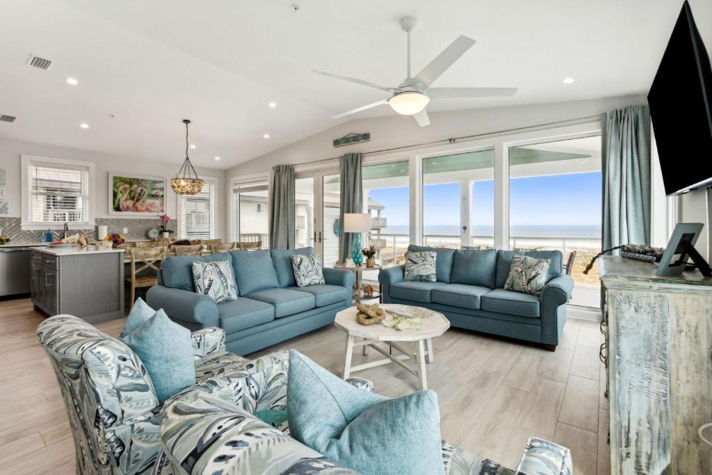 a living room with blue couches and a table at Ocean Lookout 3 - Heated Pool, Beachfront Deck, Stunning Ocean Views in Fernandina Beach