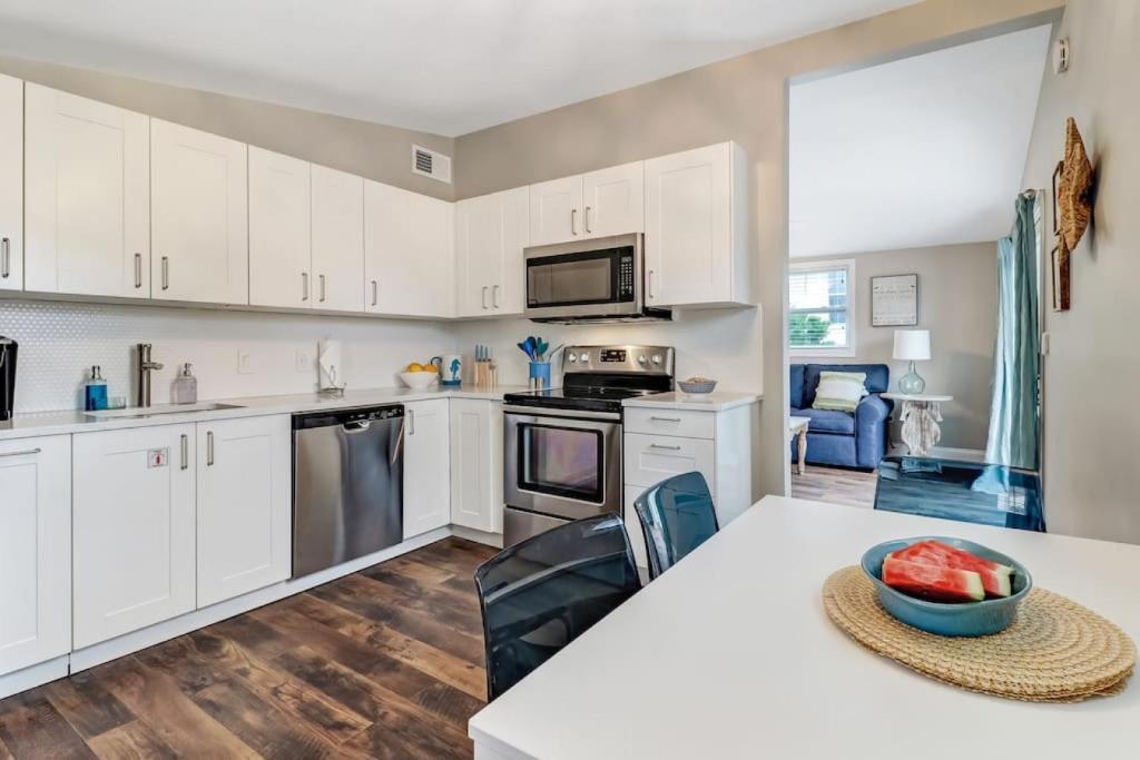 a kitchen with white cabinets and a table with a bowl of fruit at Tropical Beach Bungalow Up - 3 bedrooms - Across Street from Beach - Deck in Fernandina Beach