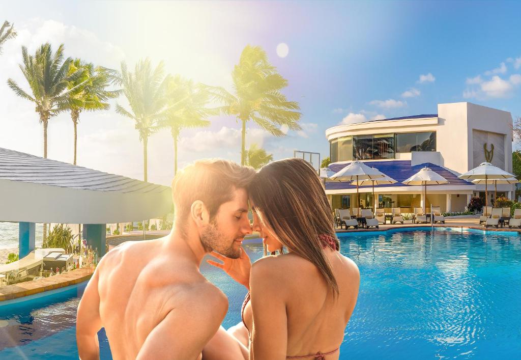 a man and a woman sitting next to a swimming pool at Desire Riviera Maya Pearl Resort All Inclusive - Couples Only in Puerto Morelos