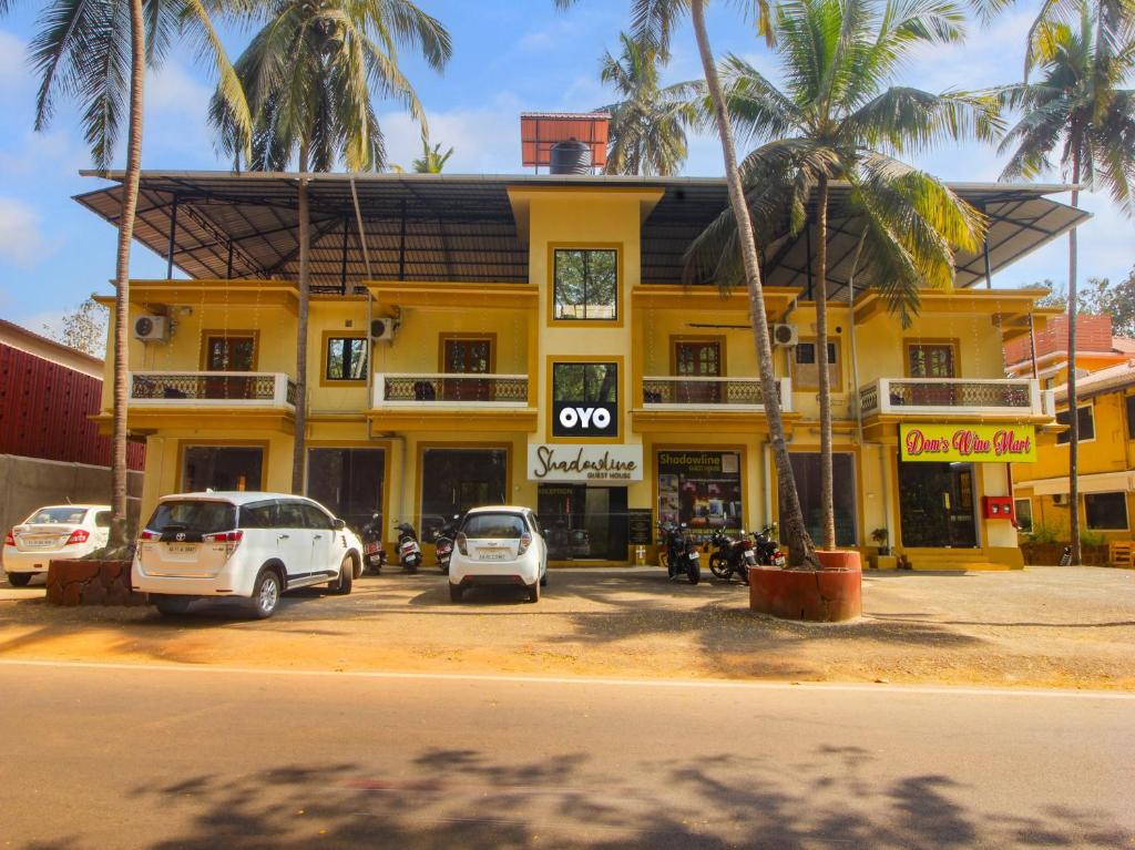 un edificio amarillo con coches estacionados frente a él en Collection O Shadowline Guesthouse en Goa