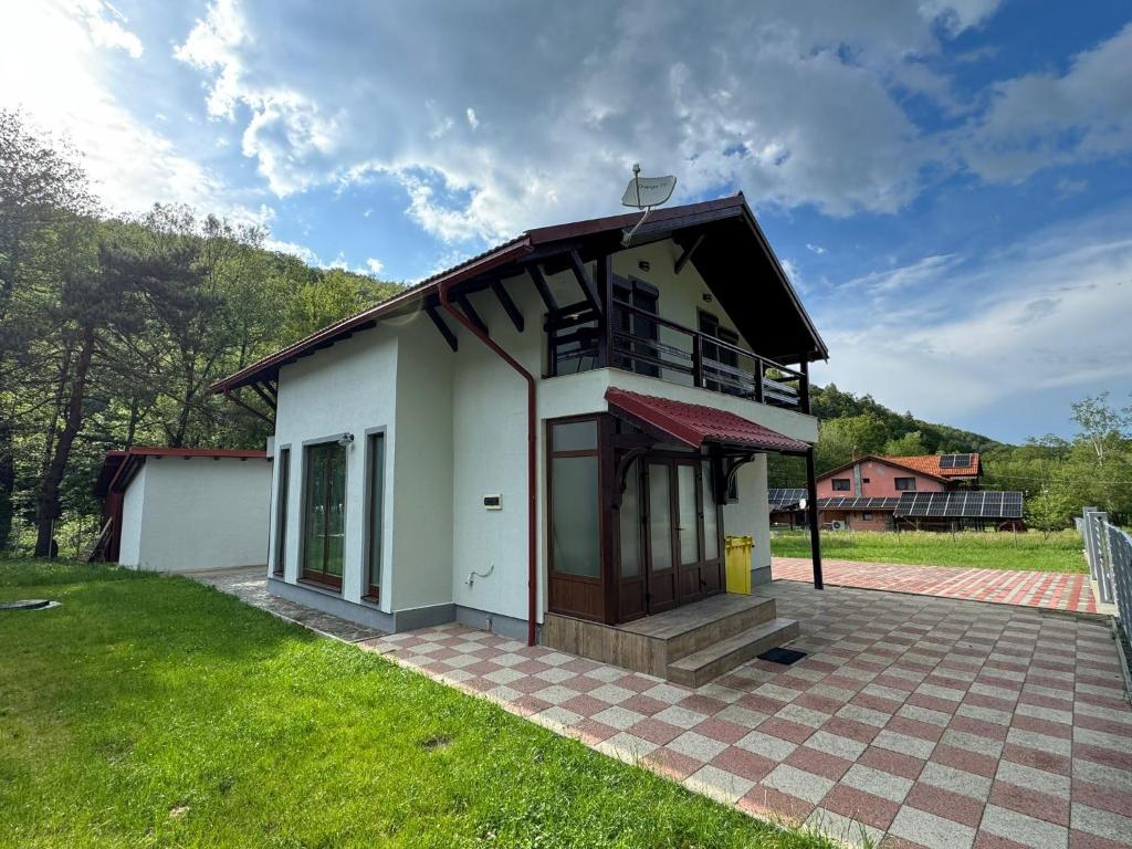 a small white house with a roof on a field at Cabana LUCDAR Valiug Crivaia in Văliug