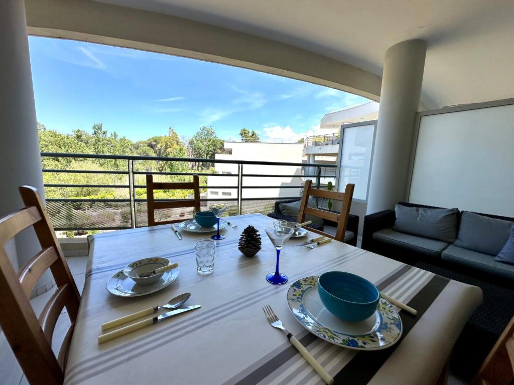 - une table avec des assiettes et des bols sur le balcon dans l'établissement Appartement Rivages 100m plage CALVI, à Calvi