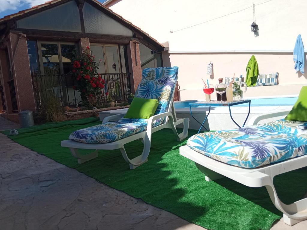 dos sillas sentadas en una alfombra verde junto a una piscina en casa rural El Burrillo, en Cuenca